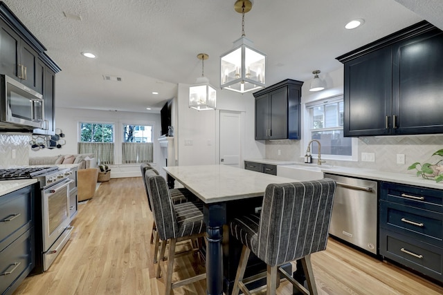 412 Merrill St, Houston, TX 77009 - kitchen featuring appliances with stainless steel finishes, a sink, open floor plan, light wood-type flooring, and tasteful backsplash