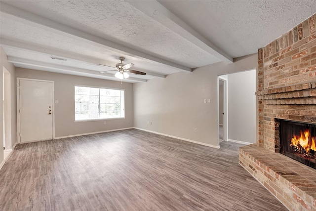 9507 Rannock Way, Spring, TX 77379 - unfurnished living room featuring a brick fireplace, a textured ceiling, wood finished floors, baseboards, and a ceiling fan
