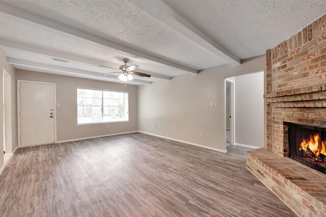 9507 Rannock Way, Spring, TX 77379 - unfurnished living room with a brick fireplace, a textured ceiling, baseboards, wood finished floors, and a ceiling fan
