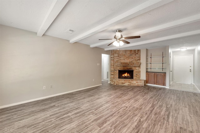 9507 Rannock Way, Spring, TX 77379 - unfurnished living room featuring beamed ceiling, baseboards, wood finished floors, ceiling fan, and a fireplace