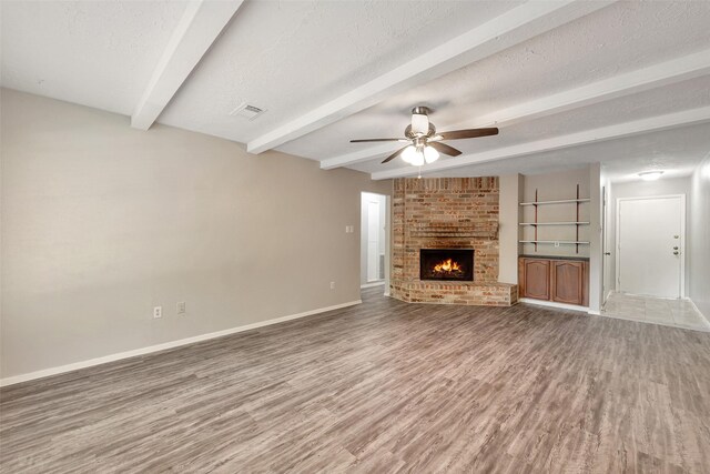 9507 Rannock Way, Spring, TX 77379 - unfurnished living room featuring beam ceiling, baseboards, wood finished floors, a ceiling fan, and a fireplace