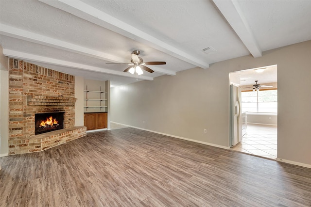 9507 Rannock Way, Spring, TX 77379 - unfurnished living room featuring a ceiling fan, wood finished floors, baseboards, beamed ceiling, and a textured ceiling