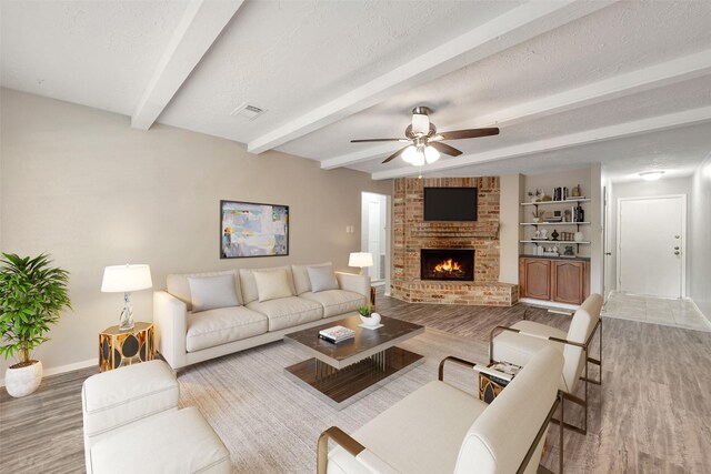 9507 Rannock Way, Spring, TX 77379 - living area featuring wood finished floors, baseboards, beamed ceiling, a ceiling fan, and a brick fireplace