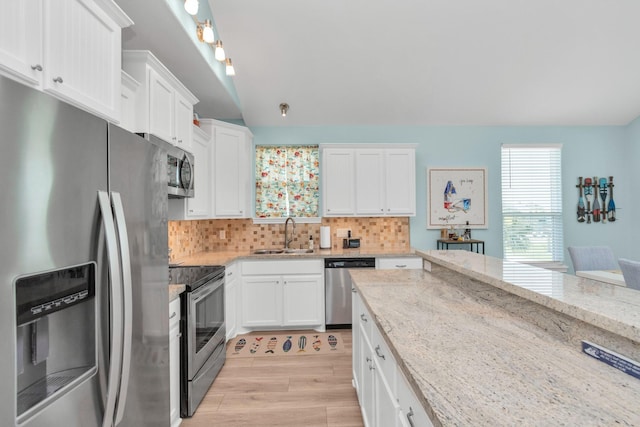 4019 Ector Dr, Galveston, TX 77554 - kitchen featuring appliances with stainless steel finishes, a sink, white cabinets, light wood-type flooring, and lofted ceiling