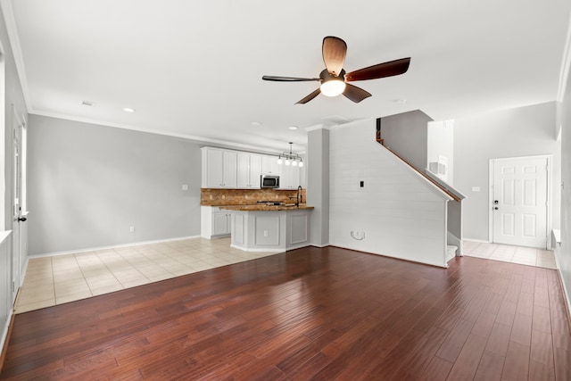 137 E Summerhaze Cir, The Woodlands, TX 77382 - unfurnished living room with a ceiling fan, light wood-style floors, stairway, baseboards, and a sink