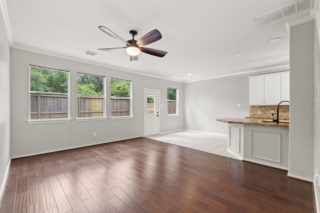 137 E Summerhaze Cir, The Woodlands, TX 77382 - unfurnished living room featuring a ceiling fan, baseboards, crown molding, a sink, and wood finished floors