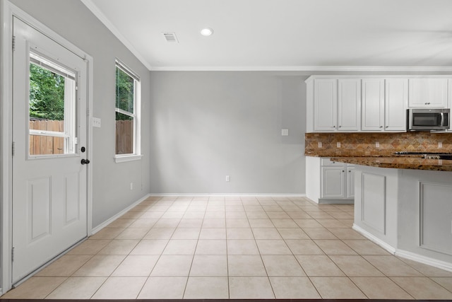 137 E Summerhaze Cir, The Woodlands, TX 77382 - kitchen featuring stainless steel microwave, tasteful backsplash, crown molding, white cabinets, and light tile patterned floors