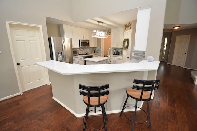 19026 Rustling Ridge Ln, Tomball, TX 77377 - kitchen with appliances with stainless steel finishes, backsplash, a peninsula, and dark wood-style floors