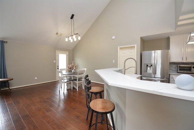 19026 Rustling Ridge Ln, Tomball, TX 77377 - kitchen featuring stainless steel refrigerator with ice dispenser, high vaulted ceiling, a kitchen breakfast bar, white cabinets, and dark wood-style floors