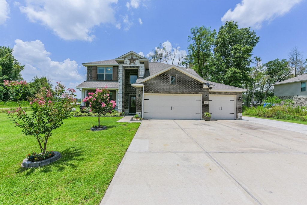 579 Rd 6618, Dayton, TX 77535 - view of front facade with an attached garage, driveway, a front yard, brick siding, and a shingled roof