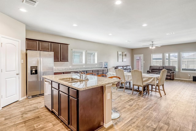 22624 Theodoli Dr, Katy, TX 77449 - kitchen featuring stainless steel appliances, a sink, open floor plan, light wood-style flooring, and a kitchen island with sink