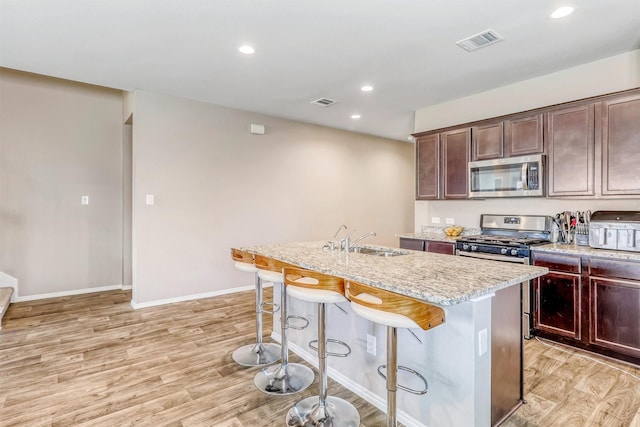 22624 Theodoli Dr, Katy, TX 77449 - kitchen with appliances with stainless steel finishes, a sink, light wood finished floors, a kitchen bar, and recessed lighting