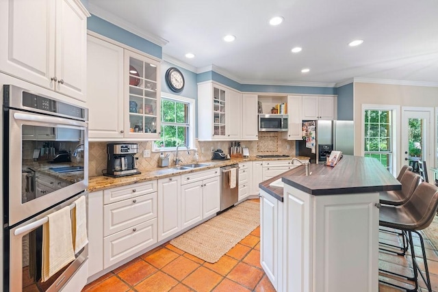 1908 Columbine Dr, Lufkin, TX 75904 - kitchen with appliances with stainless steel finishes, ornamental molding, recessed lighting, a kitchen breakfast bar, and decorative backsplash
