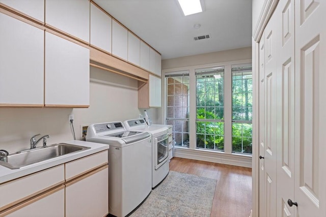 1908 Columbine Dr, Lufkin, TX 75904 - laundry room with washing machine and dryer, cabinet space, light wood finished floors, and healthy amount of natural light