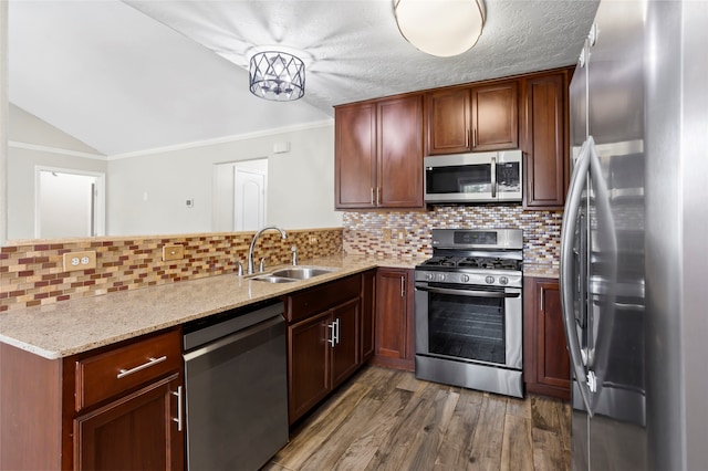 5000 Old Castle Ln, Dickinson, TX 77539 - kitchen with appliances with stainless steel finishes, a sink, a peninsula, wood finished floors, and tasteful backsplash