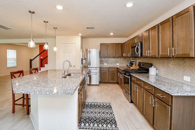 4827 Ranleagh Ct, Katy, TX 77493 - kitchen with appliances with stainless steel finishes, a sink, a breakfast bar area, tasteful backsplash, and light stone counters