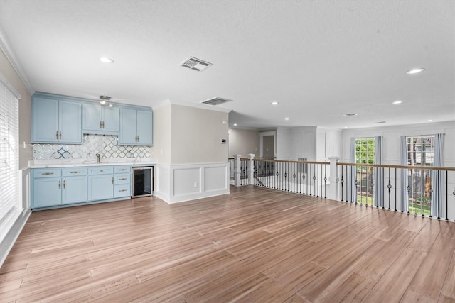 5523 Theall Rd, Houston, TX 77066 - kitchen with beverage cooler, blue cabinetry, a decorative wall, light wood-style flooring, and a sink