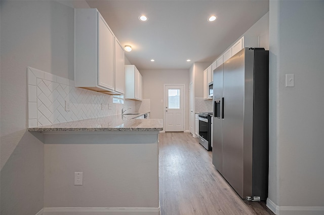 24710 Landolfi Dr, Katy, TX 77493 - kitchen with appliances with stainless steel finishes, light wood-style flooring, tasteful backsplash, white cabinetry, and recessed lighting