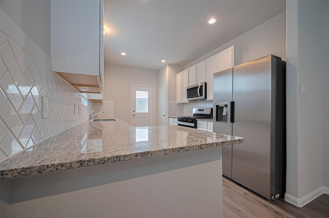24710 Landolfi Dr, Katy, TX 77493 - kitchen featuring appliances with stainless steel finishes, light wood-style flooring, light stone counters, white cabinetry, and tasteful backsplash