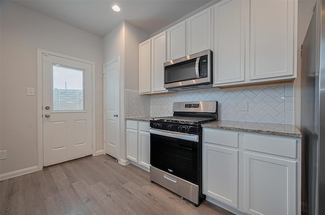 24710 Landolfi Dr, Katy, TX 77493 - kitchen with appliances with stainless steel finishes, light wood-type flooring, tasteful backsplash, white cabinetry, and light stone countertops