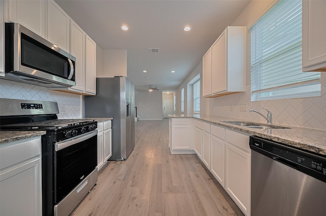 24710 Landolfi Dr, Katy, TX 77493 - kitchen with appliances with stainless steel finishes, a sink, a ceiling fan, white cabinetry, and light stone counters
