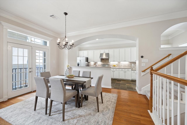 5405 Blossom St, Houston, TX 77007 - dining space with crown molding, stairway, a chandelier, arched walkways, and wood finished floors