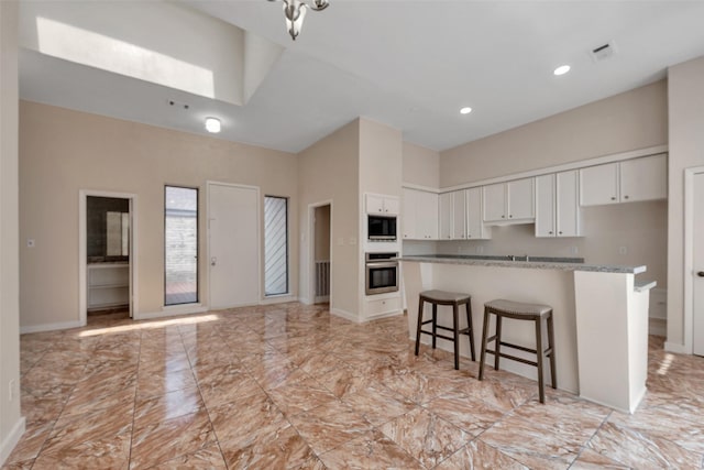4111 Wildacres Dr, Houston, TX 77072 - kitchen featuring built in microwave, stainless steel oven, baseboards, white cabinets, and a kitchen bar