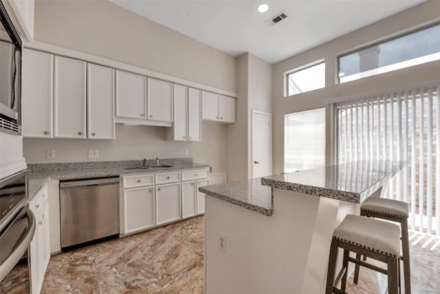 4111 Wildacres Dr, Houston, TX 77072 - kitchen featuring stainless steel appliances, a kitchen breakfast bar, white cabinets, light stone counters, and a sink