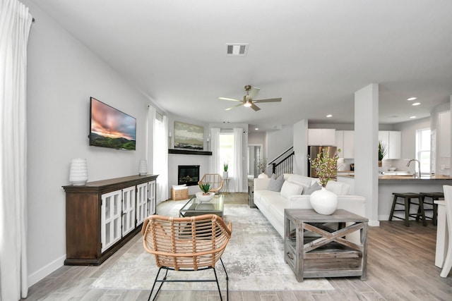 2142 Emerald Diamond Ct, Fresno, TX 77545 - living room featuring light wood-type flooring, a ceiling fan, a glass covered fireplace, recessed lighting, and baseboards