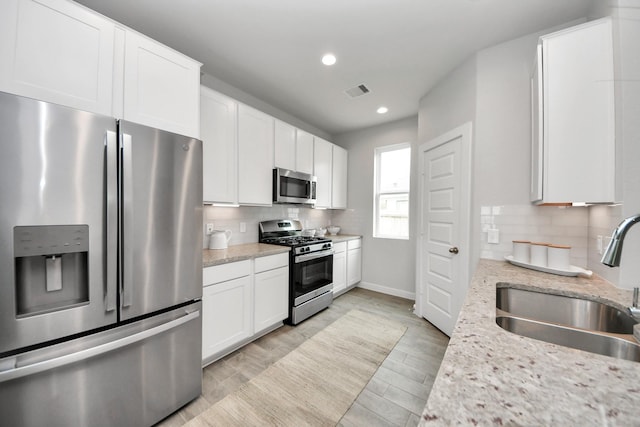 2142 Emerald Diamond Ct, Fresno, TX 77545 - kitchen featuring appliances with stainless steel finishes, a sink, decorative backsplash, white cabinets, and baseboards