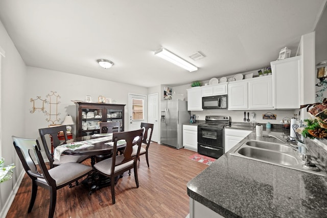 4603 Poppy Crest Ct, Richmond, TX 77469 - kitchen with black appliances, a sink, dark countertops, light wood-style flooring, and white cabinets