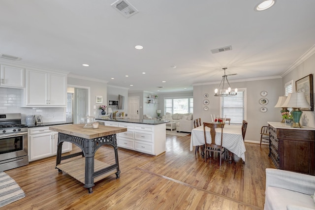 1023 Waltway Dr, Houston, TX 77008 - kitchen featuring stainless steel range with gas cooktop, dark countertops, a peninsula, open floor plan, and white cabinetry
