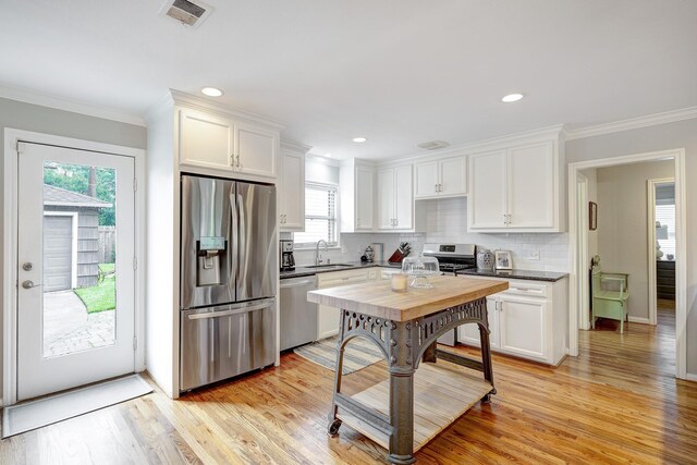 1023 Waltway Dr, Houston, TX 77008 - kitchen featuring appliances with stainless steel finishes, a sink, white cabinets, tasteful backsplash, and crown molding