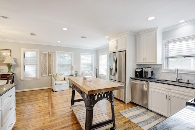 1023 Waltway Dr, Houston, TX 77008 - kitchen featuring stainless steel appliances, a sink, plenty of natural light, light wood-style floors, and ornamental molding