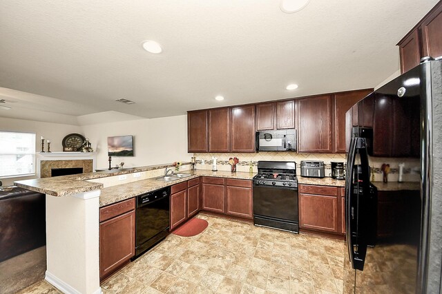 15319 Meandering Post Trl, Houston, TX 77044 - kitchen featuring black appliances, a peninsula, open floor plan, a sink, and a tiled fireplace