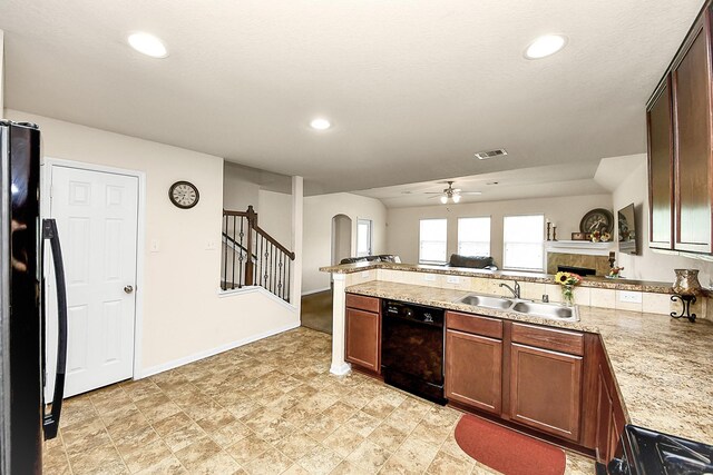 15319 Meandering Post Trl, Houston, TX 77044 - kitchen with black appliances, arched walkways, a sink, a peninsula, and a tiled fireplace