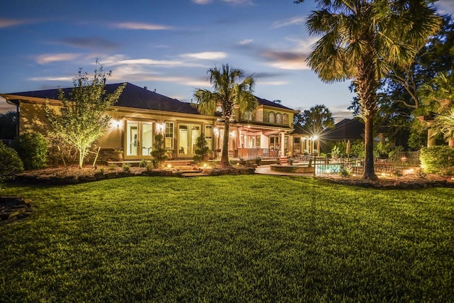 20806 Kings Crown Ct, Humble, TX 77346 - back of property at dusk featuring french doors and a lawn