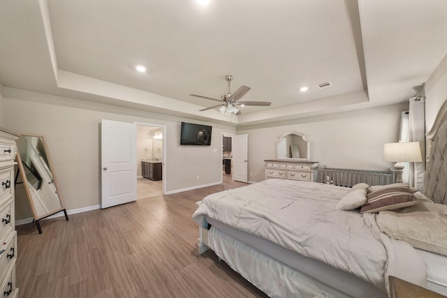 26410 Yaupon Crk, Magnolia, TX 77355 - bedroom featuring a raised ceiling, wood finished floors, baseboards, connected bathroom, and recessed lighting