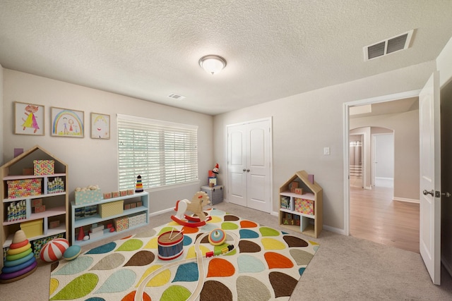 26410 Yaupon Crk, Magnolia, TX 77355 - recreation room featuring arched walkways, carpet flooring, a textured ceiling, and baseboards