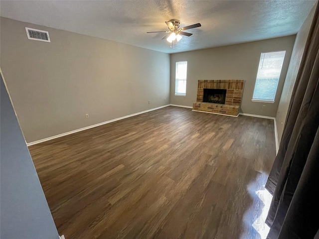 10555 Turtlewood Ct Unit 610, Houston, TX 77072 - unfurnished living room featuring dark wood-style flooring, a ceiling fan, baseboards, a textured ceiling, and a brick fireplace