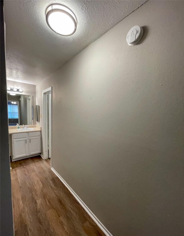 10555 Turtlewood Ct Unit 610, Houston, TX 77072 - corridor featuring dark wood-style floors, a sink, baseboards, and a textured ceiling