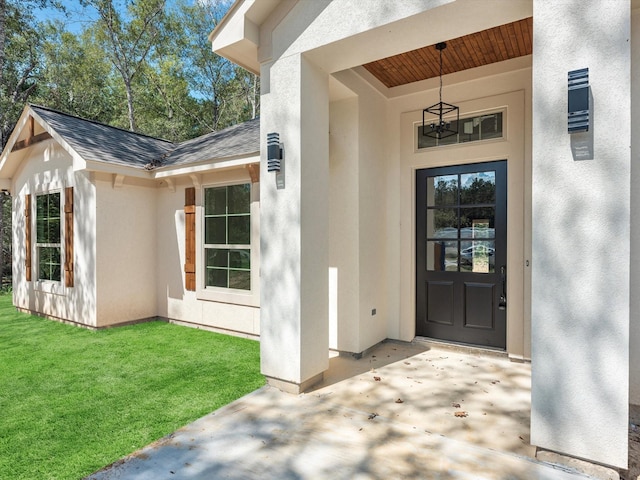 1197 Rd 660, Dayton, TX 77535 - view of exterior entry featuring roof with shingles, a yard, and stucco siding