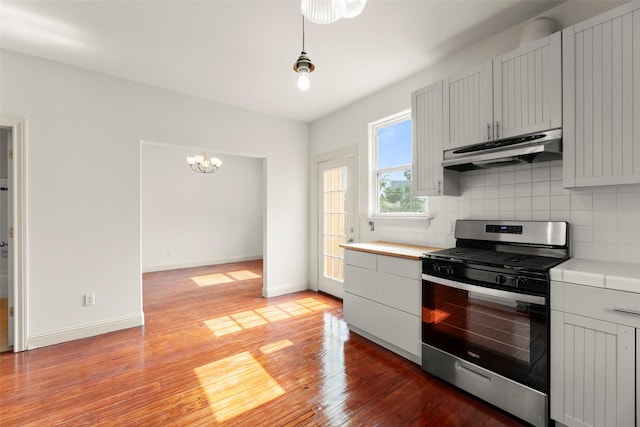 4015 Garrott St, Houston, TX 77006 - kitchen with stainless steel gas stove, under cabinet range hood, light wood-style flooring, tasteful backsplash, and a chandelier