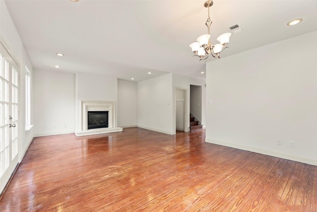 4015 Garrott St, Houston, TX 77006 - unfurnished living room with a chandelier, light wood finished floors, a glass covered fireplace, recessed lighting, and baseboards