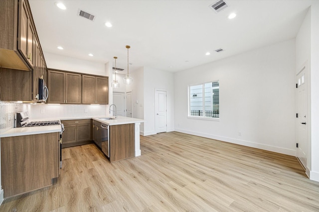 1544 W Tidwell Rd, Houston, TX 77091 - kitchen featuring stainless steel appliances, a peninsula, light wood-type flooring, tasteful backsplash, and baseboards