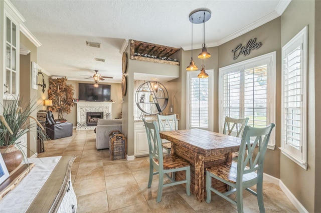 1914 Tipperary Dr, Deer Park, TX 77536 - dining space featuring a ceiling fan, a fireplace with raised hearth, light tile patterned floors, ornamental molding, and baseboards