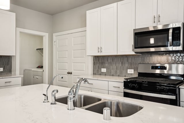 18737 Bliss Pl, New Caney, TX 77357 - kitchen with appliances with stainless steel finishes, separate washer and dryer, a sink, and white cabinets