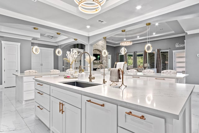 807 Steele Rd Unit A, Highlands, TX 77562 - kitchen featuring a raised ceiling, a large island with sink, a sink, light stone counters, and decorative light fixtures