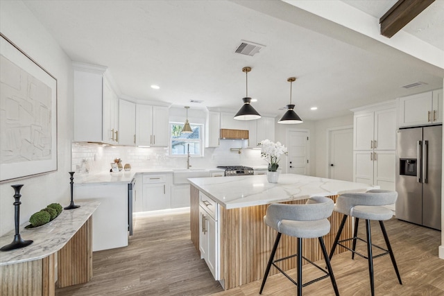 10830 Bob White Dr, Houston, TX 77096 - kitchen featuring appliances with stainless steel finishes, a sink, backsplash, light wood-type flooring, and a kitchen island
