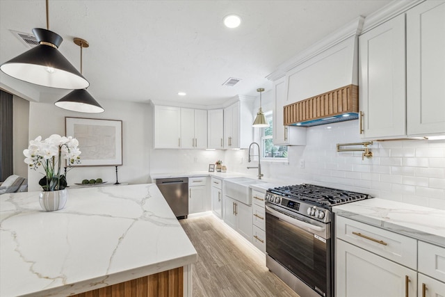 10830 Bob White Dr, Houston, TX 77096 - kitchen with appliances with stainless steel finishes, a sink, white cabinets, light wood-style floors, and decorative backsplash